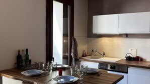 Een moderne keuken met witte kastjes, een houten eettafel gedekt voor vier personen, en een raam met gordijnen.