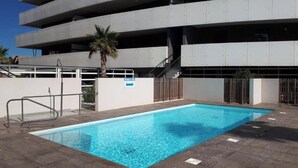 A swimming pool with a metal ladder and a palm tree nearby. - Modern apartment with AC 100 m from the beach for 6 pers (Le Barcarès)