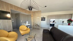 Een moderne woonkamer met een bruine leren bank, twee gele fauteuils en een glazen salontafel.
