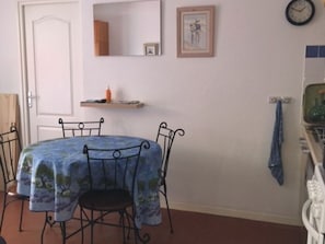 A dining area with a round table covered by a blue tablecloth, surrounded by four chairs. - T3 Apartment 500m from beach, private parking, pets allowed (Le Barcarès)