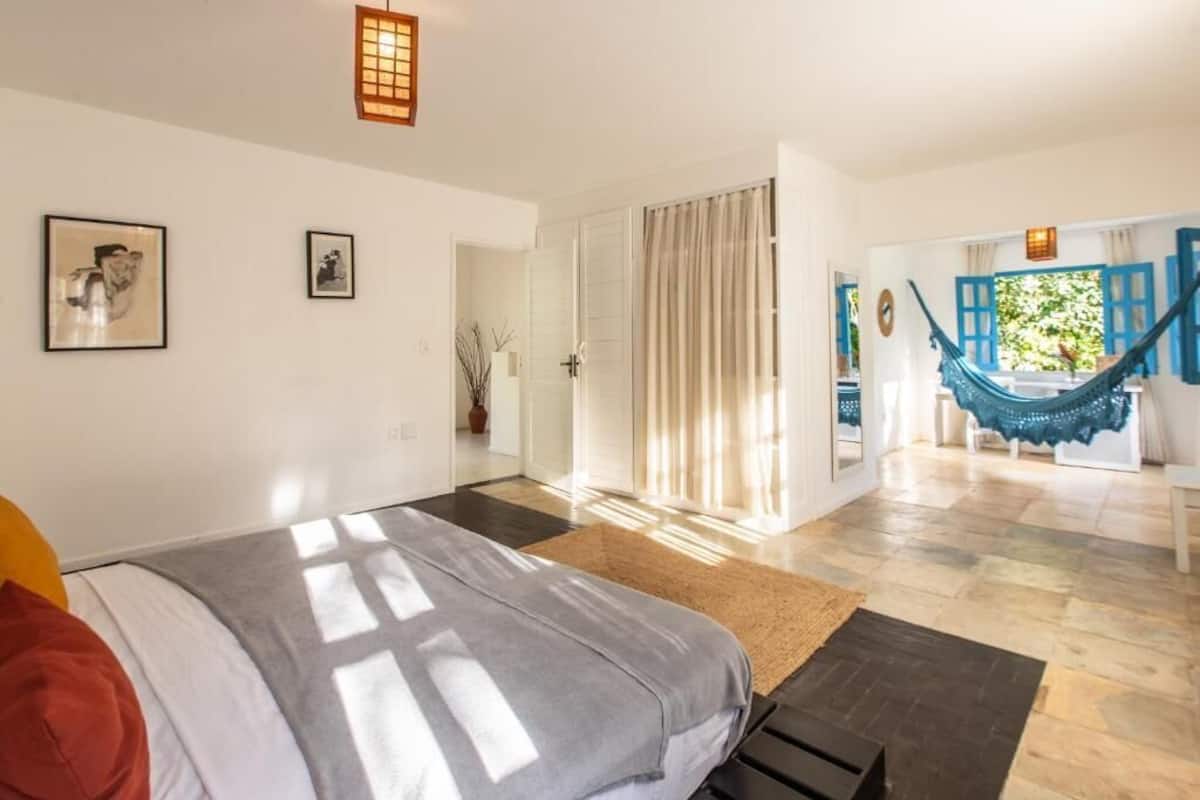 Un dormitorio con cama, una hamaca y vistas al exterior.