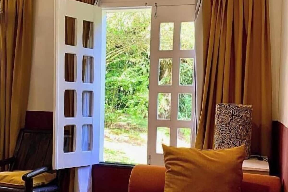 Una habitación con cama, una silla y una ventana con cortinas.