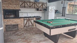 Una mesa de billar en una habitación con pared de piedra y una parrilla empotrada.