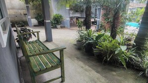 Un espacio al aire libre cubierto con un banco, plantas en macetas y vistas a una piscina.