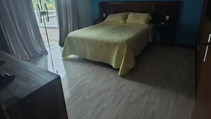 Un dormitorio con cama, escritorio y vista a través de una puerta de cristal.