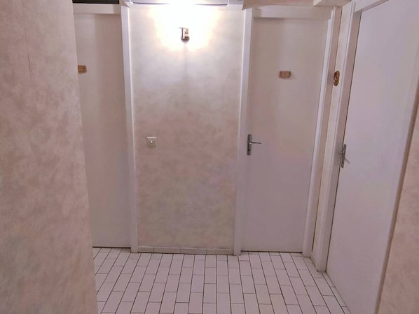 A hallway with a closed door, a light switch, and a tiled floor. - 3-room apartment with air conditioning and parking in central Canet-Plage (Canet-Plage)