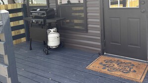 A small outdoor kitchen area with a grill, a propane tank, and a window overlooking a residential street. - A peaceful 3-bedroom house in beautiful downtown Rogers (Rogers)