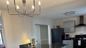 A modern kitchen with a central island, stainless steel appliances, and a chandelier. - A peaceful 3-bedroom house in beautiful downtown Rogers (Rogers)