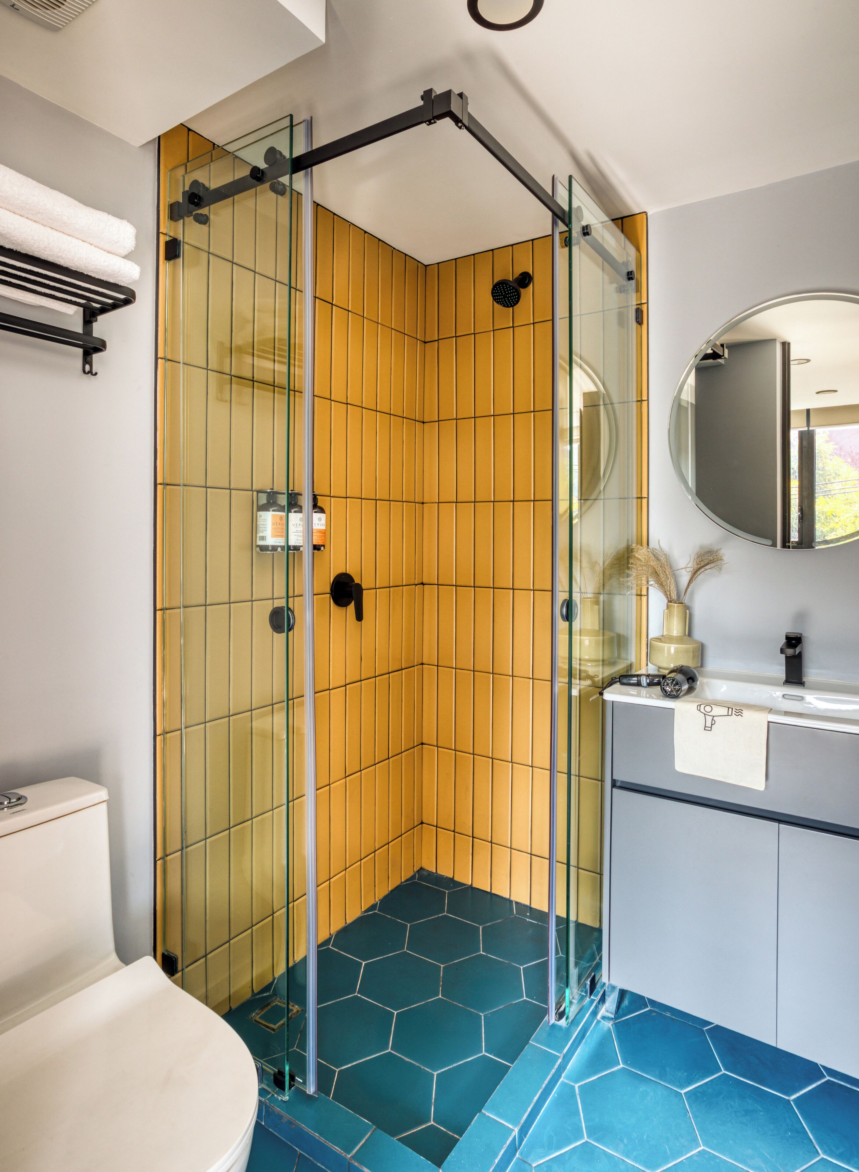 A bathroom with a glass-enclosed shower, a toilet, and a sink with a mirror.