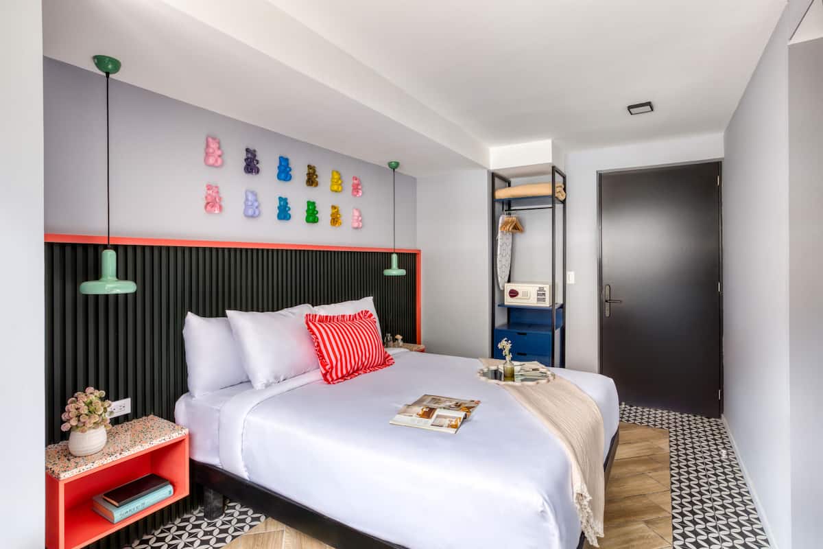 A modern bedroom with a bed, bedside tables, a wall-mounted shelf, and a door.
