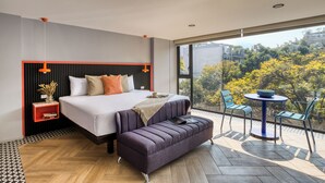 A modern bedroom with a large bed, a sofa, and a small table with chairs. - ULIV Condesa (Mexico City)