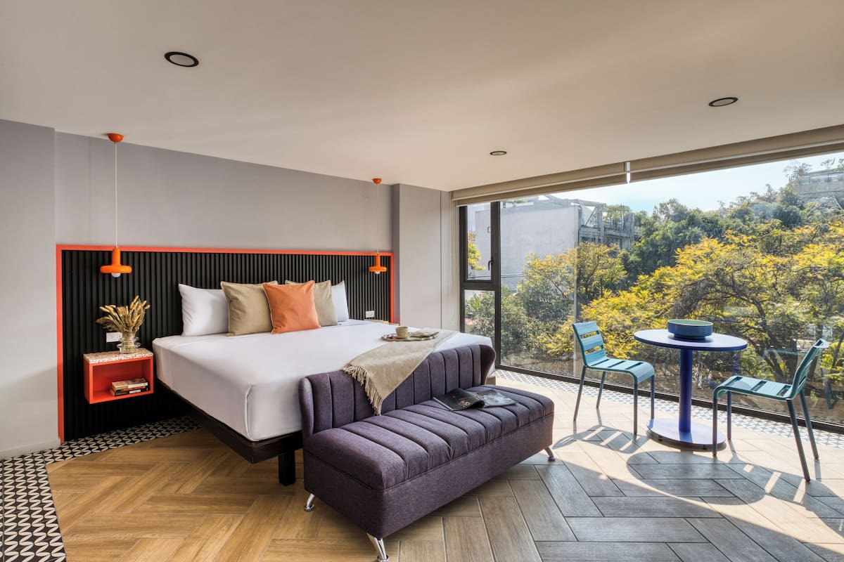 A modern bedroom with a large bed, a sofa, and a small table with chairs.