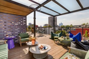Terraza en la azotea con asientos al aire libre, una pérgola y vistas a la ciudad.