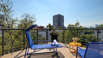 En balkong med blå loungestolar, ett litet bord med en vas och en krukväxt.