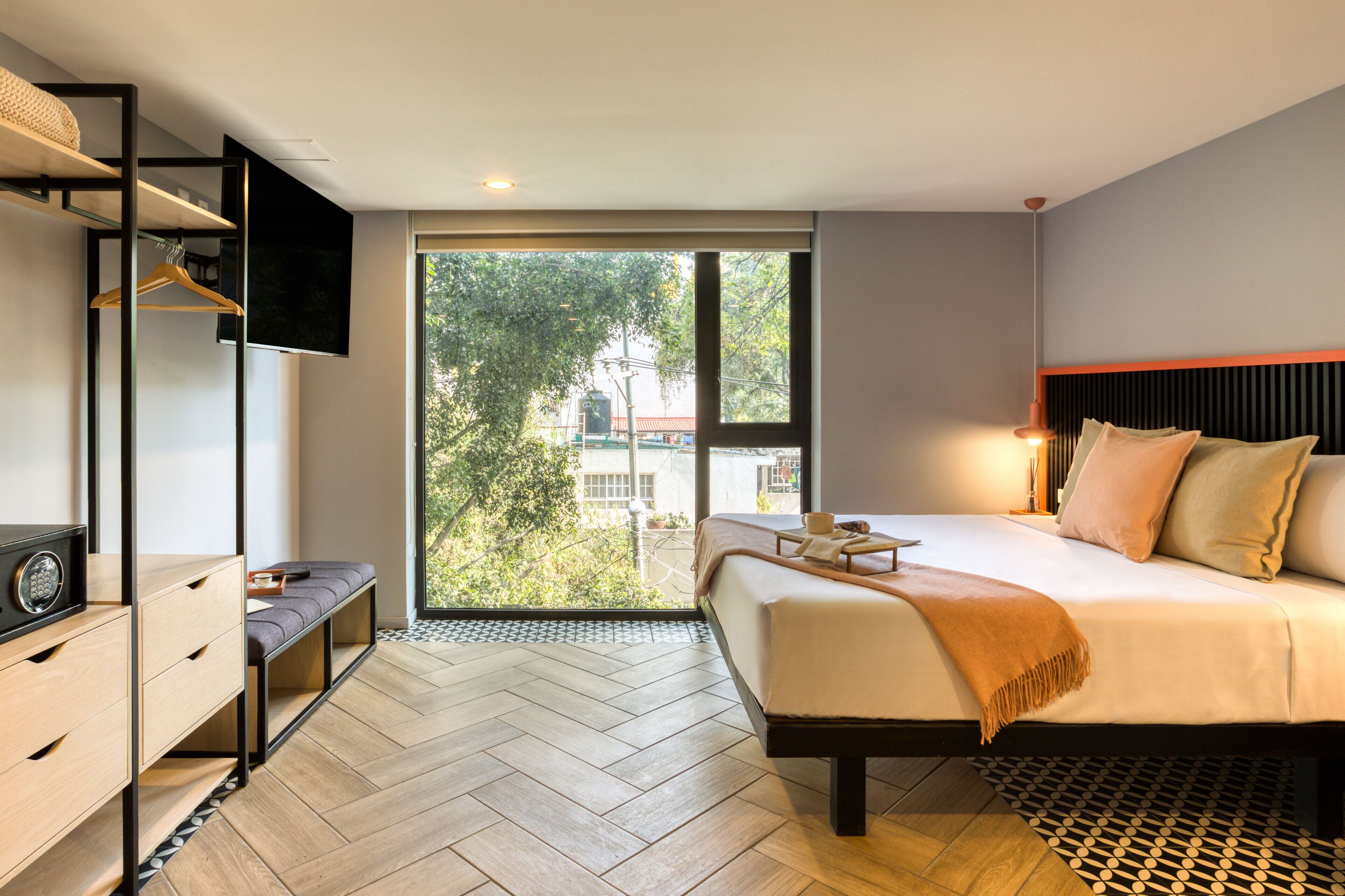 A modern bedroom with a bed, bedside table, TV, and a bench.