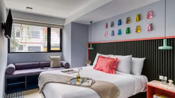 Une chambre d’hôtel moderne équipée d’un lit, d’un coin salon, d’une télévision et d’un mur décoré de motifs représentant des ours.