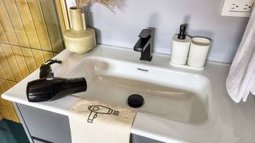 Ein Waschbecken mit Fön, Handtuch und einer Vase mit Trockenblumen.