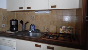 A kitchen with white cabinets, a stainless steel sink, a coffee maker, and a gas stove. - Bright 2-room apartment with private parking at Canet-Plage (Canet-Plage)