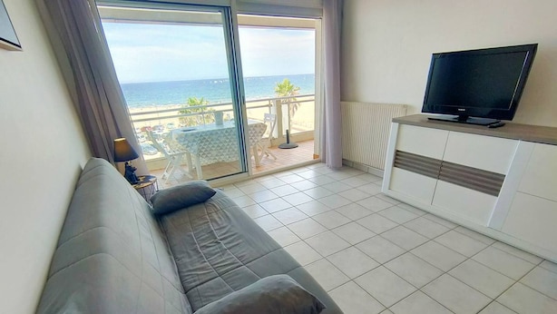 Un salon avec un canapé, un téléviseur et une vue sur la plage.