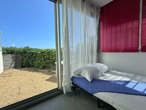Une chambre à coucher avec un lit, une fenêtre avec des rideaux et une vue sur un jardin.