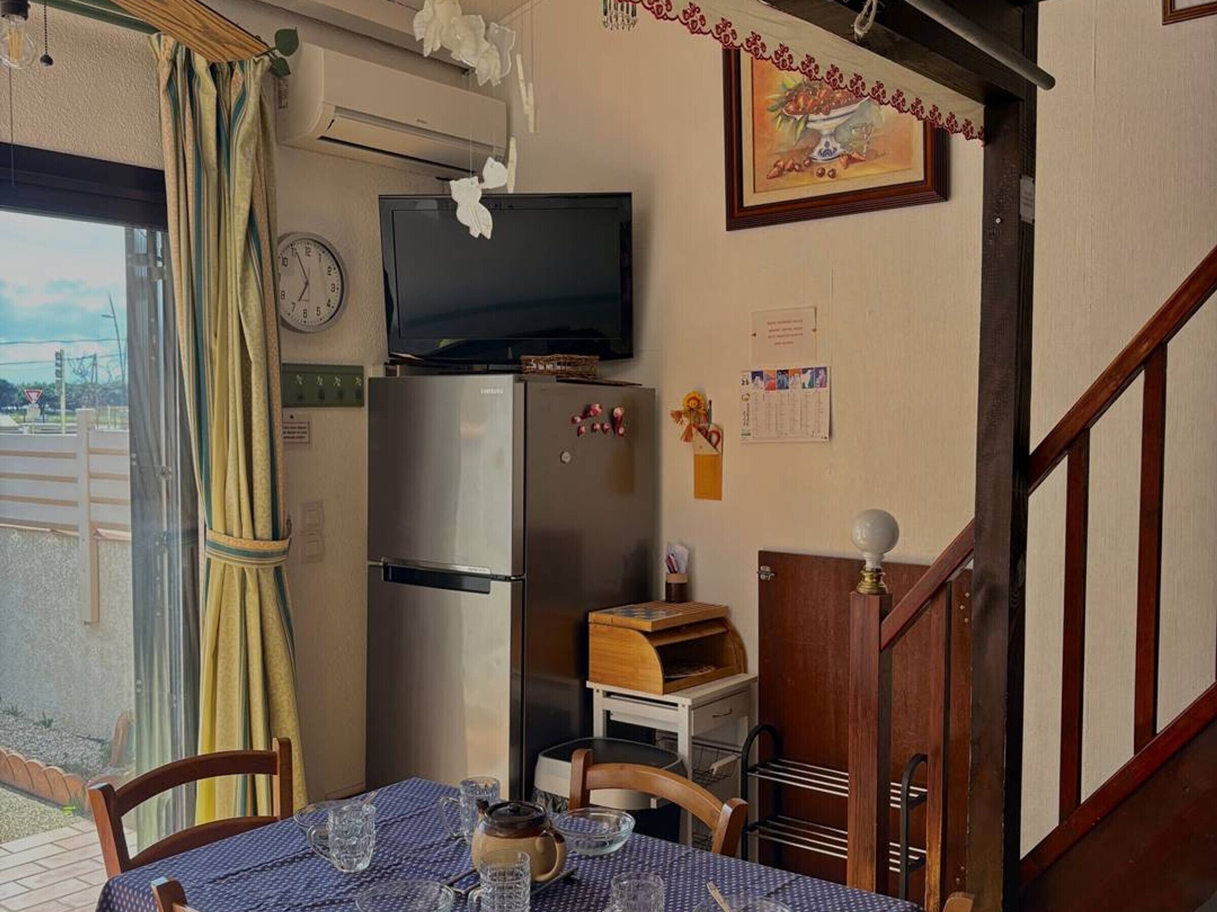 Une cuisine compacte équipée d’un réfrigérateur, d’une télévision et d’une table à manger pour quatre personnes.