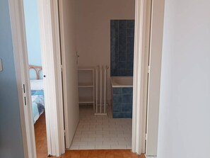 A narrow hallway leading to a bathroom with a tiled shower area and a bed visible in the adjacent room. - 2-room south-facing, terrace, 4 pers, beachfront (Canet-Plage)