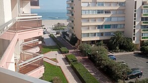 A multi-story residential building with balconies, a parking area, and a view of the beach. - 2-room south-facing, terrace, 4 pers, beachfront (Canet-Plage)