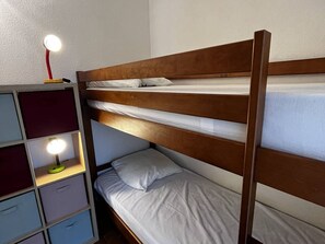 Ein Stockbett mit einem Holzkopfende und einem Nachttisch mit Lampe.