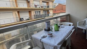 A balcony with a table set for two, a green kettle, and a coffee machine. - 2-Bedroom Flat, 50m from the beach, near center (Canet-en-Roussillon)