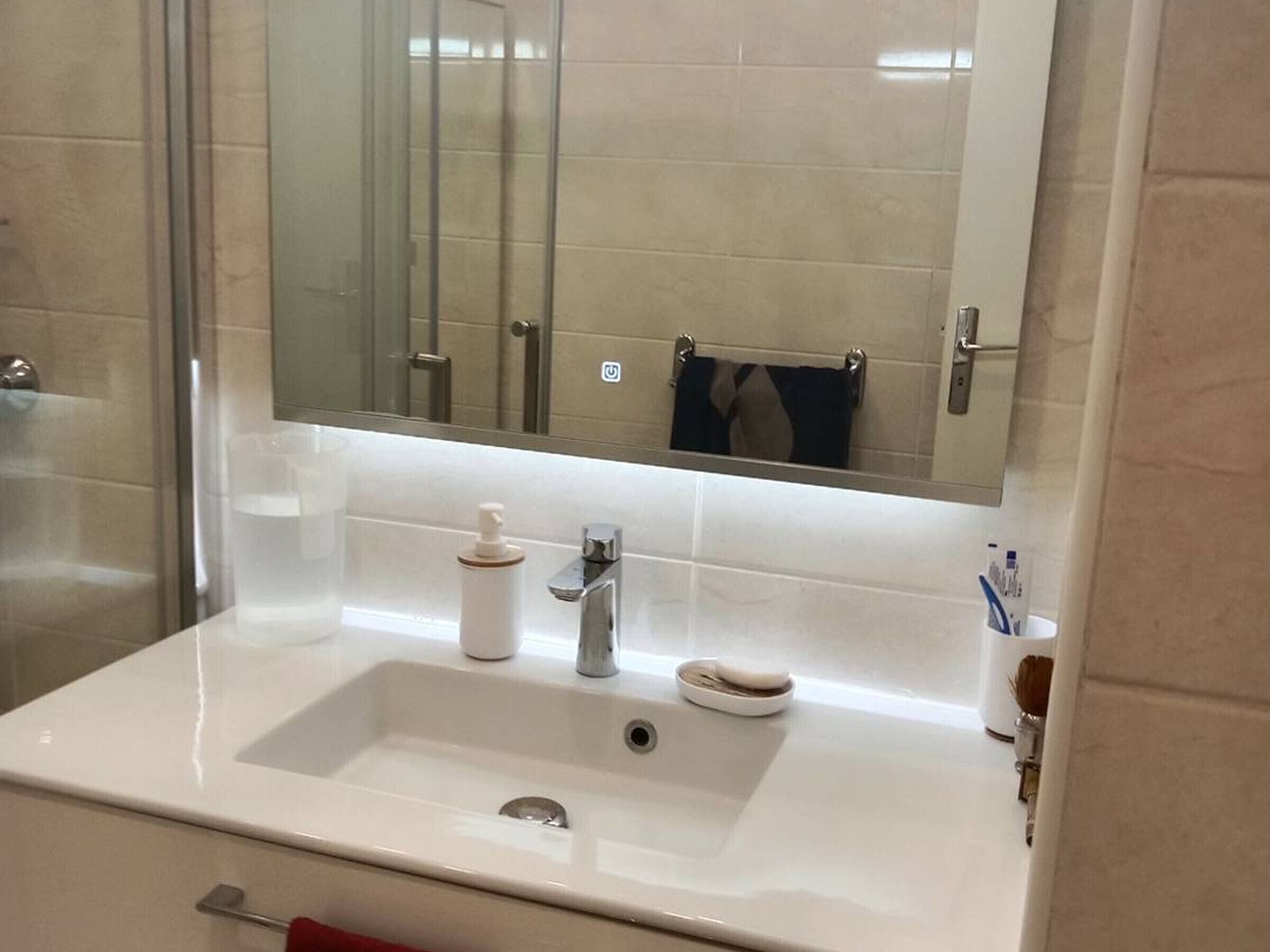 A bathroom with a white sink, a mirror, and a glass shower enclosure.