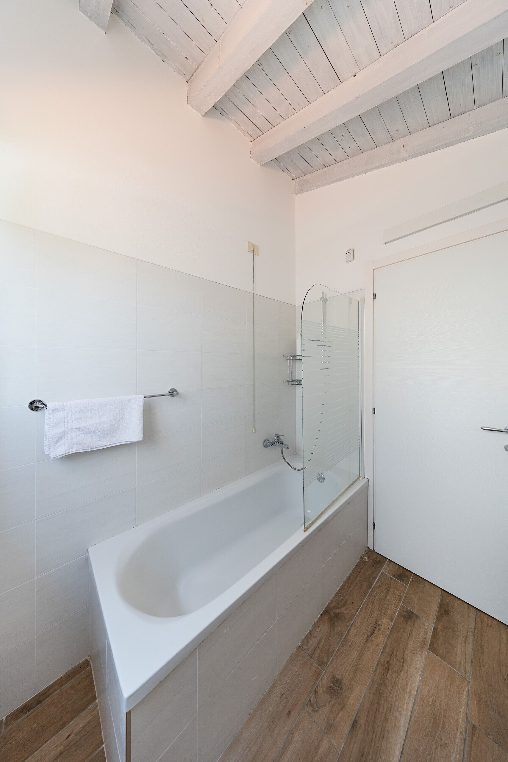 Ein Badezimmer mit einer Badewanne, einer Duschkabine aus Glas und einer weißen Tür.