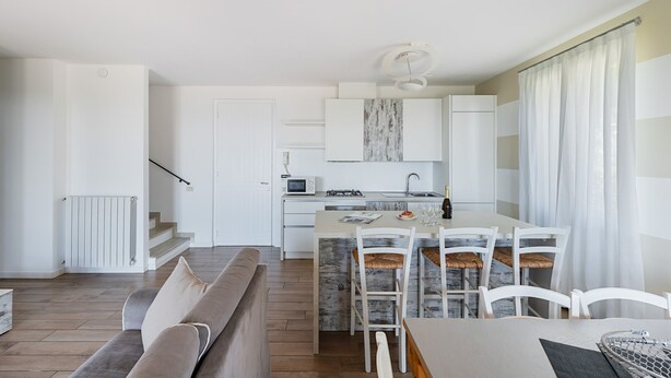 Une cuisine moderne avec des armoires blanches, un four à micro-ondes encastré et un coin repas comprenant une table et des chaises.