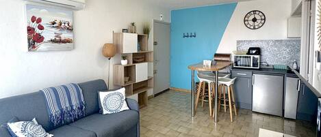 Een knus woongedeelte met een bank, een eettafel en een kitchenette.