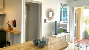 Eine moderne Küche mit Holztischplatte, einem Fernseher und einem Essbereich mit Tisch und Stühlen.