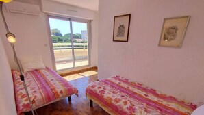 Una habitación con dos camas, una ventana y una lámpara.