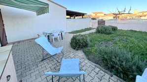 Un patio con mobiliario exterior, una zona techada y vistas de los edificios circundantes.