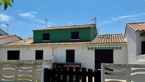 Un edificio con techo verde, paredes blancas y una verja negra.