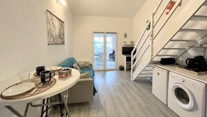 Ein kompakter Wohnbereich mit Essplatz, Sofa, Treppe und Waschbereich.