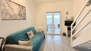 Ein Wohnzimmer mit einem türkisfarbenen Sofa, einem kleinen Tisch und einer Treppe.