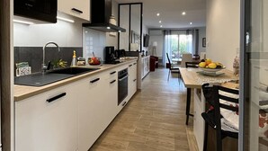 Una cocina moderna con armarios blancos, un microondas Bosch y una zona de comedor con mesa y sillas.