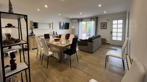 Una sala de estar moderna con comedor, un sofá y un televisor.