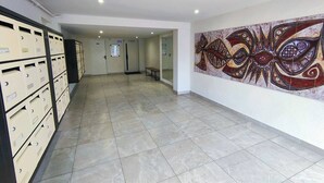 Un pasillo con armarios empotrados, suelo de baldosas y una pared con un cuadro abstracto de gran formato.
