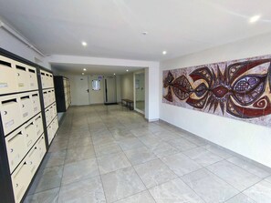 A hallway with storage cabinets, a tiled floor, and a wall with a large abstract painting. - 2-Room Apartment Sea View in Canet-Plage (Canet-Plage)