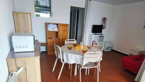 Un comedor con una mesa redonda, sillas y un televisor al fondo.