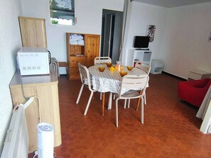 Un coin repas avec une table ronde, des chaises et un téléviseur en arrière-plan.