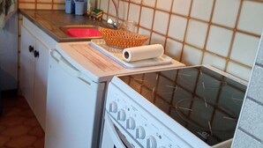 Cocina compacta con estufa blanca, lavamanos y salpicadero de azulejos.