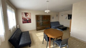 A living room with a sofa, a dining table with chairs, a cabinet, and a ceiling light. - 3-room apartment with terrace and parking in Canet-Plage (Canet-Plage)