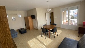 A living room with a wooden cabinet, a dining table with chairs, a sofa, and a sliding glass door leading to an outdoor area. - 3-room apartment with terrace and parking in Canet-Plage (Canet-Plage)