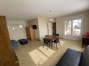 A living room with a wooden cabinet, a dining table with chairs, a sofa, and a sliding glass door leading to an outdoor area. - 3-room apartment with terrace and parking in Canet-Plage (Canet-Plage)