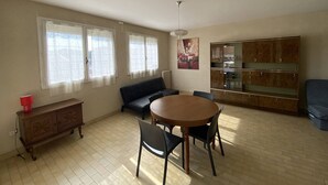 A spacious living room with a round wooden table, a sofa, and a cabinet. - 3-room apartment with terrace and parking in Canet-Plage (Canet-Plage)